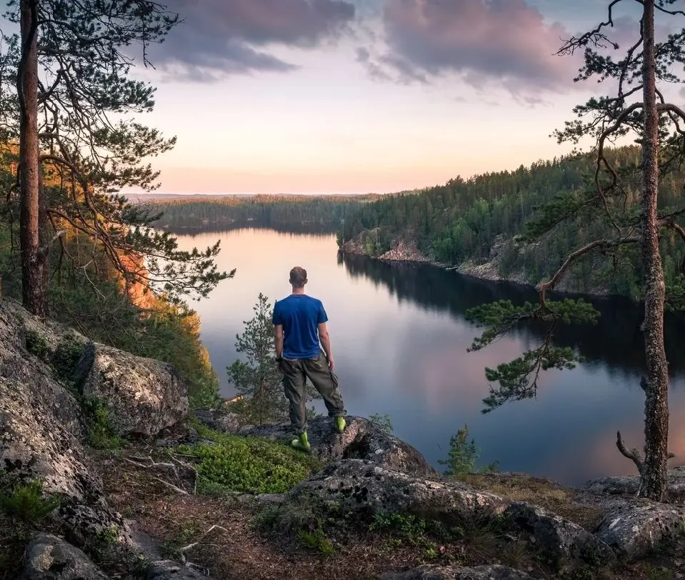 A man standing on top of a hill overlooking the water.