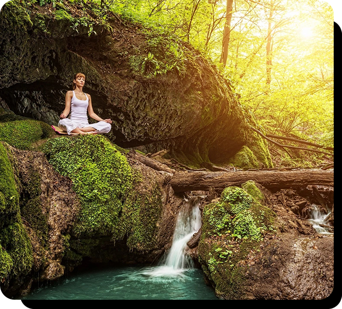 A woman sitting on top of rocks in front of a waterfall.