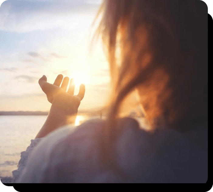 A woman is holding her hand up to the sun.