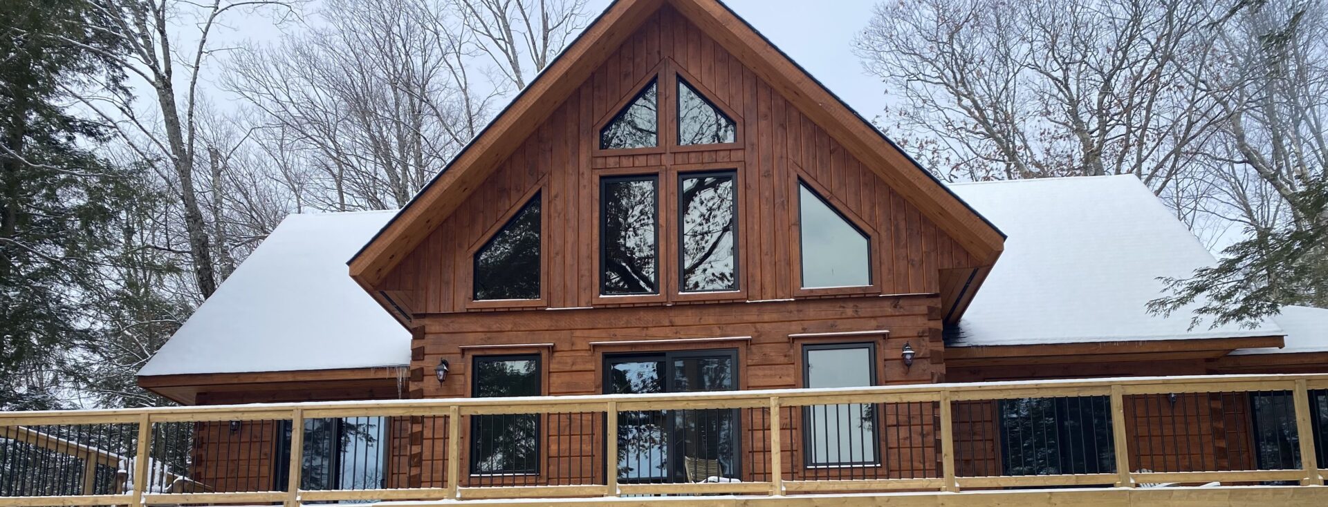 A large wooden house with windows and a deck.