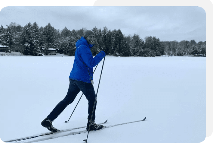 A man is skiing in the snow near trees.